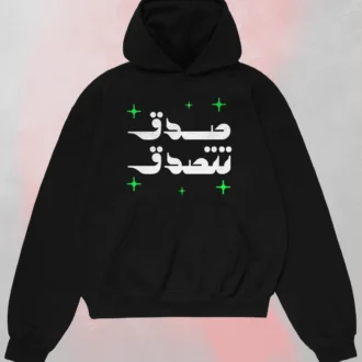 Black Arabic text black hoodie seen from the front featuring "صدق تتصدق" (Believe and you will be believed) in white calligraphy with green stars.