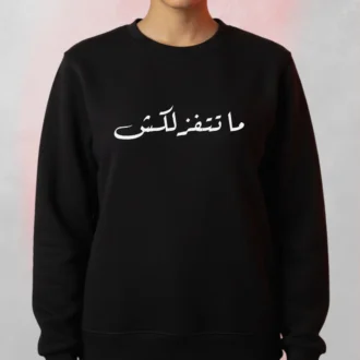 “Arabic Quote Black Sweatshirt with Arabic quote ما تتفزلكش printed on the front, worn by a model.”
