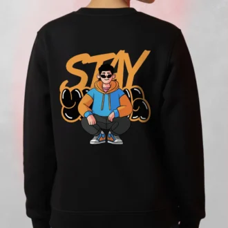 Model wearing a black Stay Urban Cartoon Sweatshirt with a cartoon character sitting in front of graffiti-style “STAY” lettering.